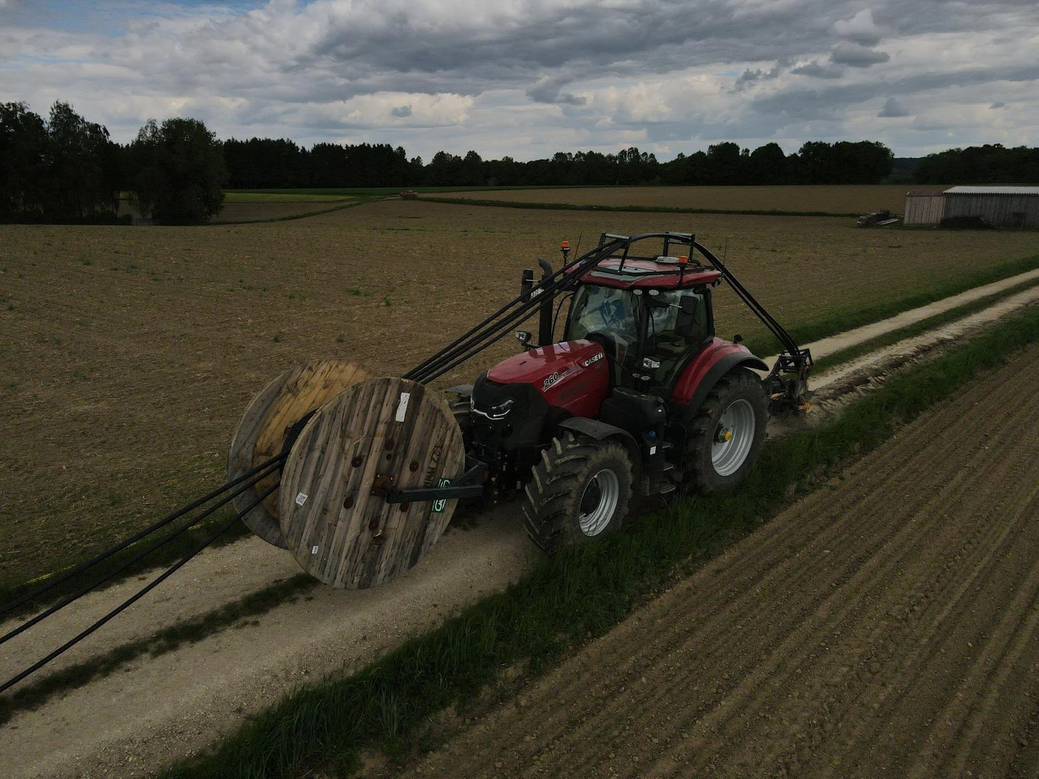 Bioenergie Fischerhöfe - Kabeltrassenbau - Traktor mit Kabelpflug verlegt Kabel auf dem Feld